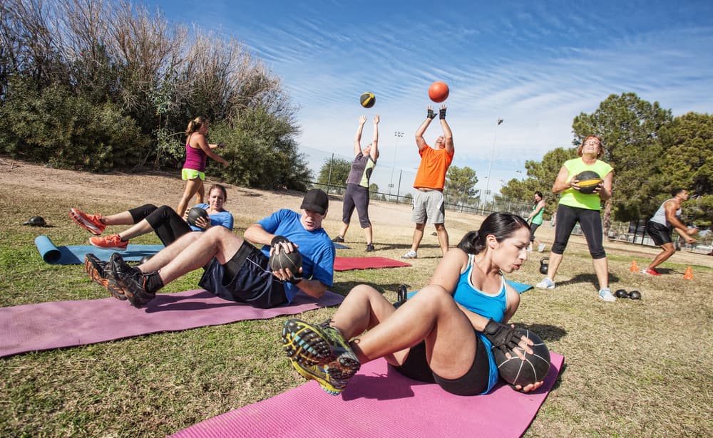 people in outdoor fitness class doing various exercises