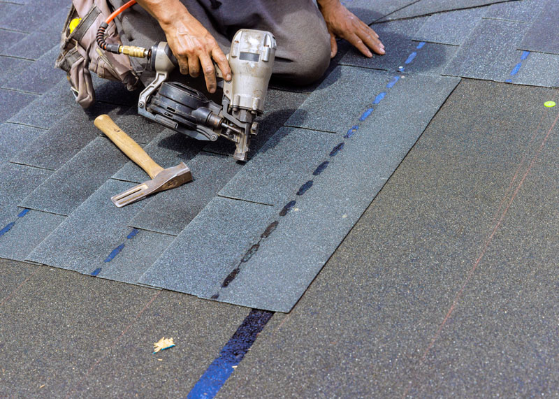 roofer kneeling while applying tiles to a roof