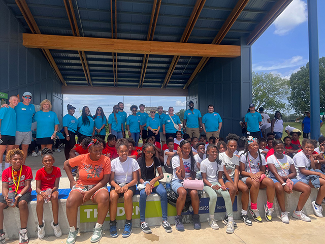 employees and children posing in amphitheater on a sunny day