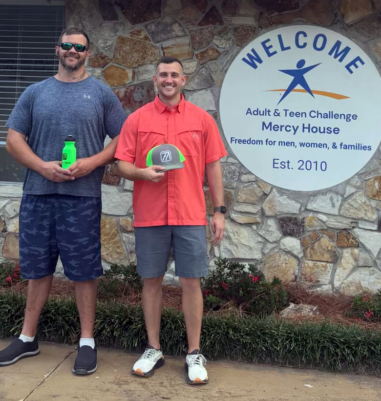 two men standing in front of the Mercy House Adult & Teen Challenge welcome sign